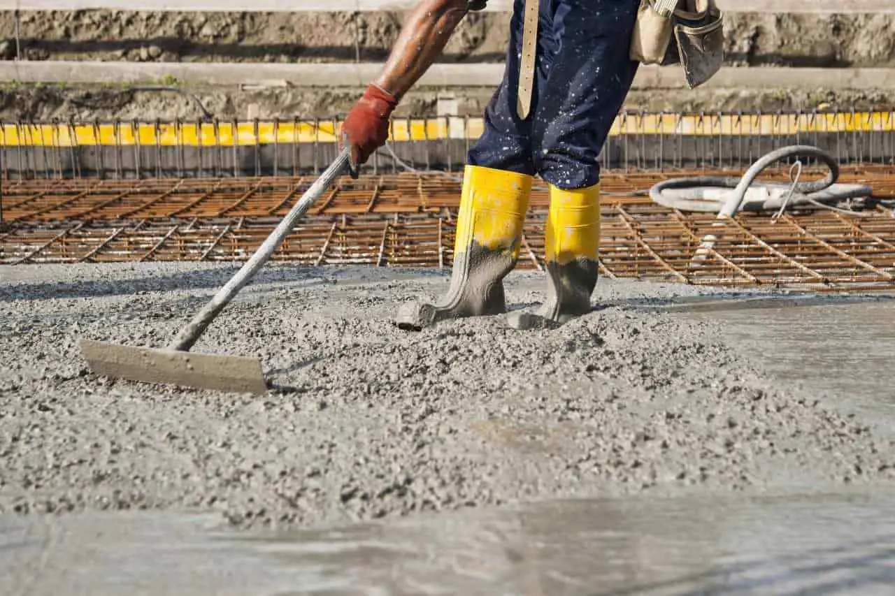 کارگر ساختمانی در حال اجرای آرماتوربندی و بتنریزی در یک دیوار بتنی